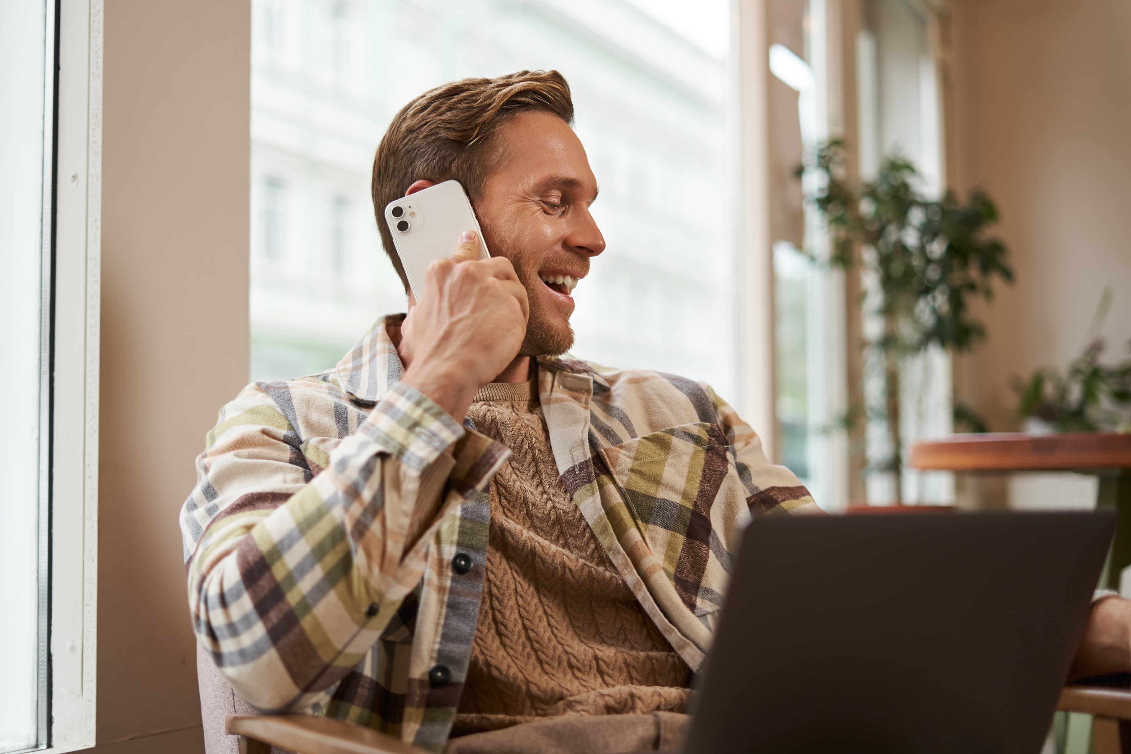Happy man using phone and laptop